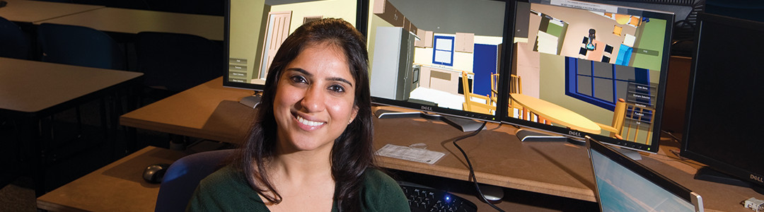 Student sitting in front of computer displaying virtual building modeling software