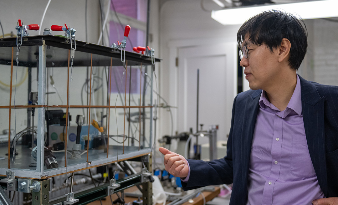 A person in a purple shirt points at a pipe structure