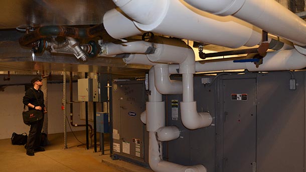 Penn State alumnus Joseph Firrantello inspects the ductwork, pipes and controls of a building's HVAC system