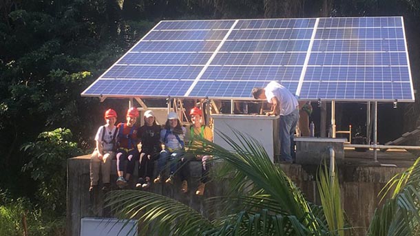 Students sit in front of an installed solar panel