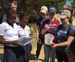 Student shows local children how to use a miniature solar water pumping system 
