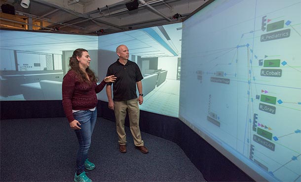 Woman talking to a man and pointing to a screen with virtual models